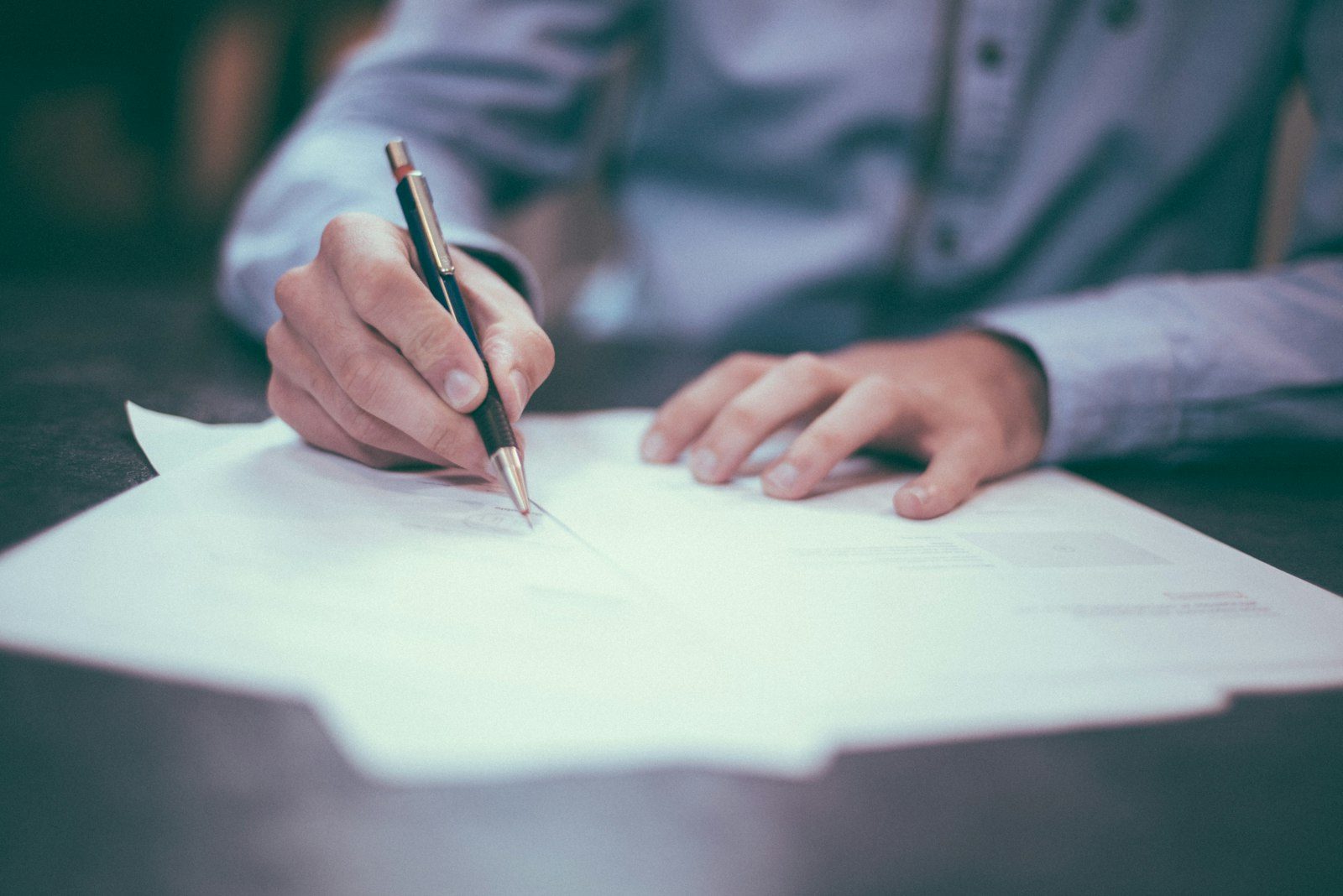 Person signing paperwork at a desk