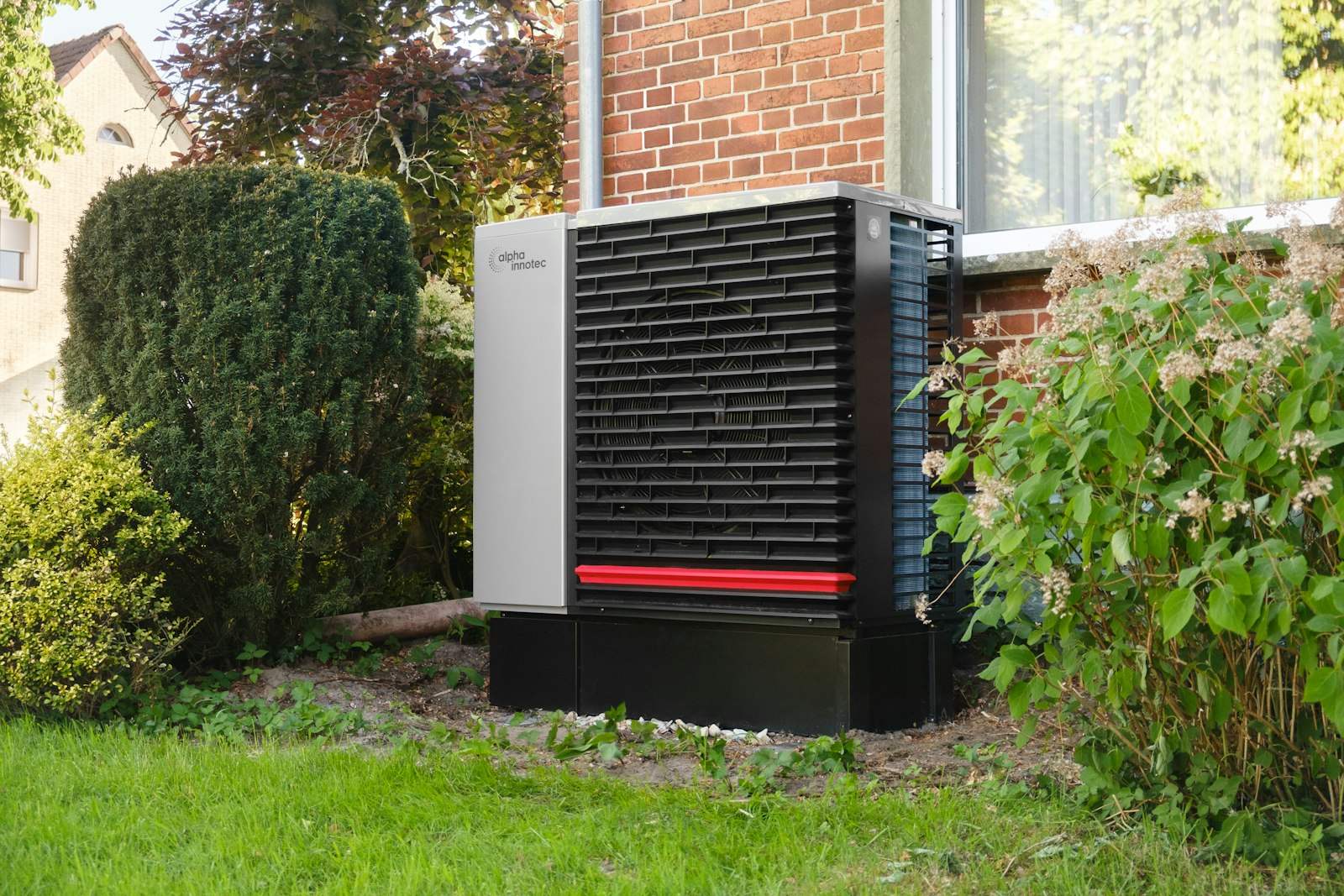 Air source heat pump unit beside a brick house